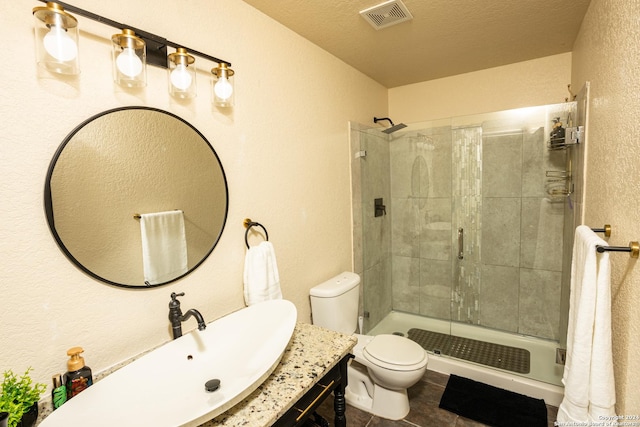 bathroom with tile patterned flooring, tiled shower, vanity, a textured ceiling, and toilet