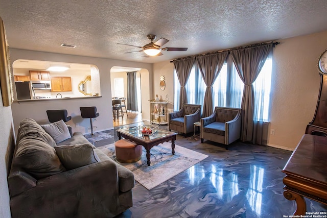 living room with ceiling fan and a textured ceiling