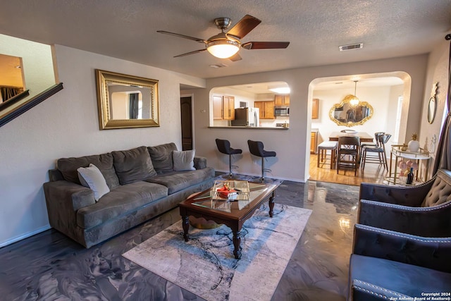 living room featuring ceiling fan and a textured ceiling