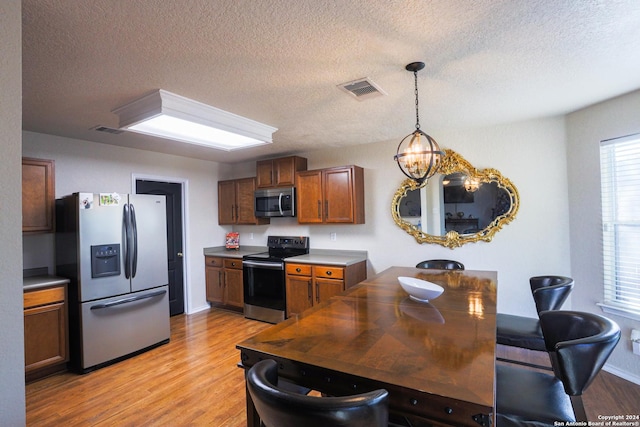 kitchen featuring appliances with stainless steel finishes, decorative light fixtures, a chandelier, and light hardwood / wood-style floors