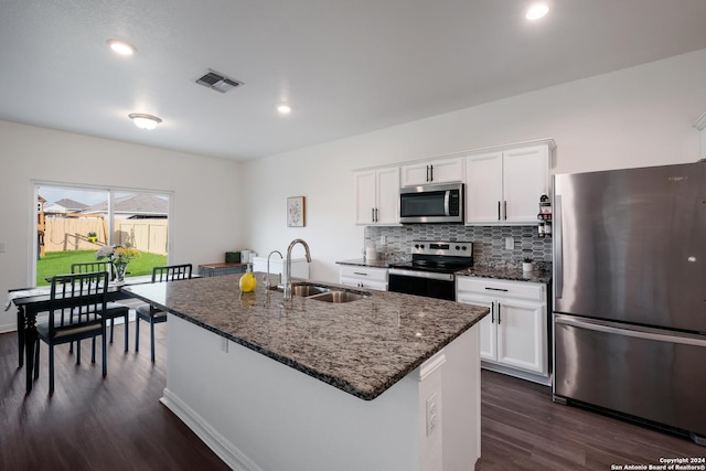 kitchen with white cabinets, sink, stainless steel appliances, and an island with sink