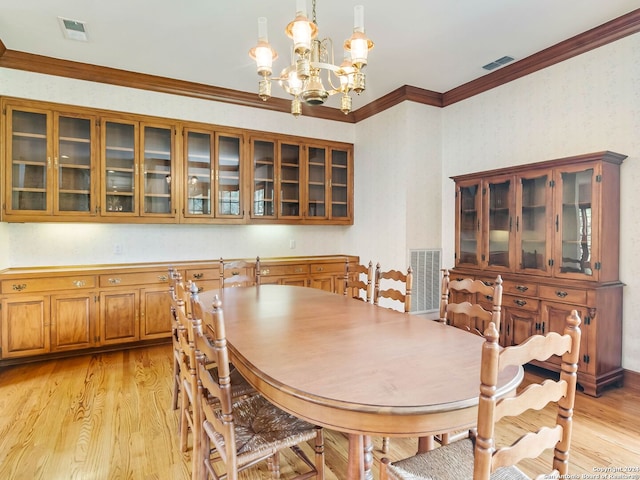 dining area featuring ornamental molding, light wood-type flooring, and a chandelier