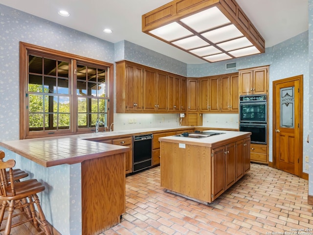 kitchen with gas cooktop, sink, a kitchen island, tile counters, and double oven