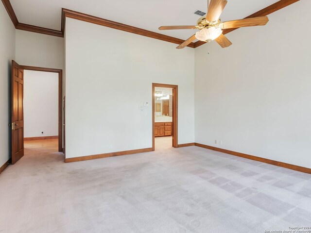 spare room with crown molding, ceiling fan, carpet flooring, and a towering ceiling