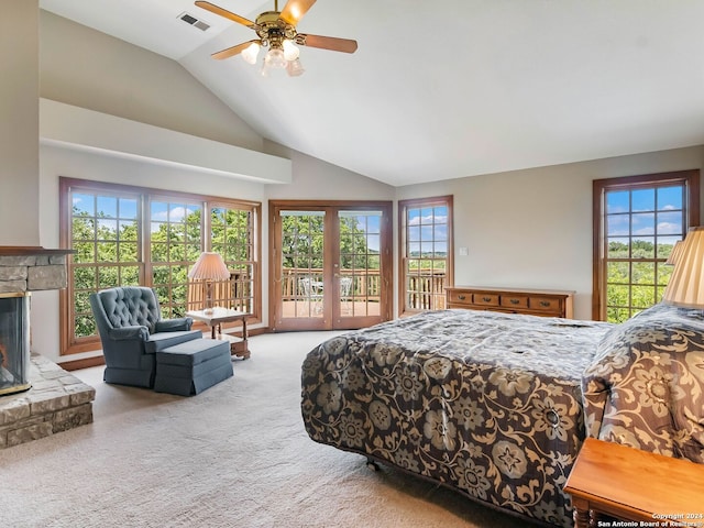 bedroom featuring multiple windows, carpet, a stone fireplace, and ceiling fan