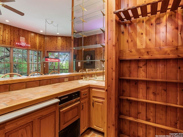 interior space featuring wooden walls, sink, hanging light fixtures, butcher block counters, and ceiling fan