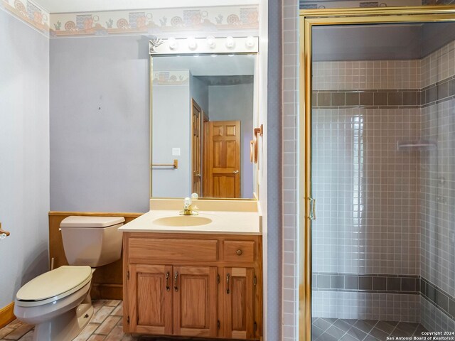 bathroom with vanity, a shower with shower door, toilet, and tile patterned floors