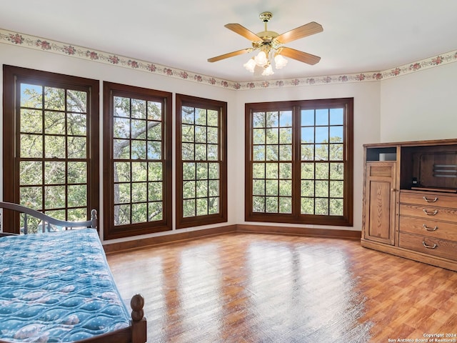 unfurnished bedroom featuring ceiling fan, multiple windows, and hardwood / wood-style flooring