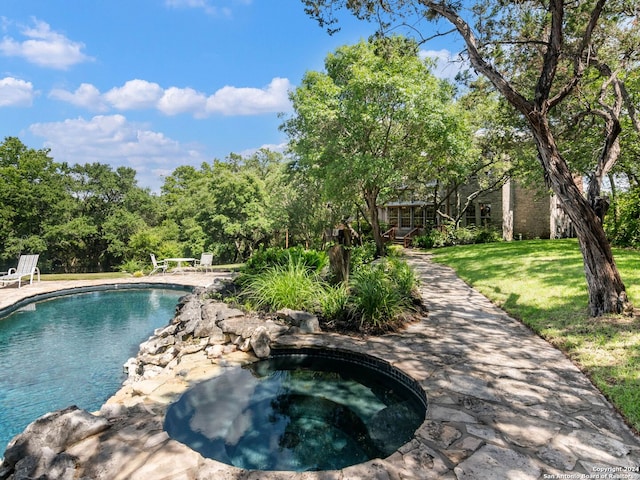 view of swimming pool with an in ground hot tub and a yard