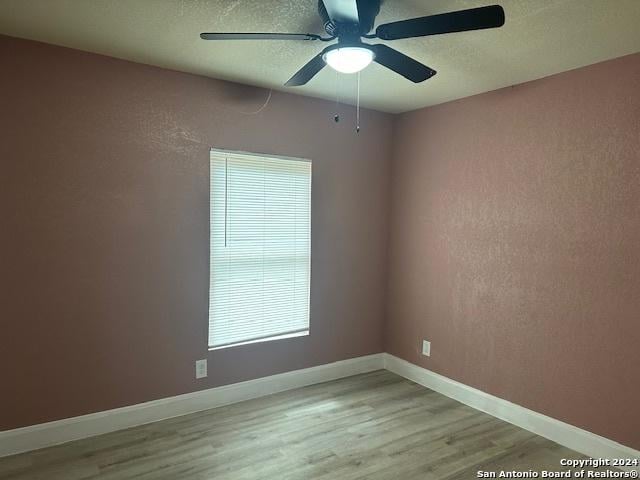 empty room with ceiling fan and light hardwood / wood-style floors