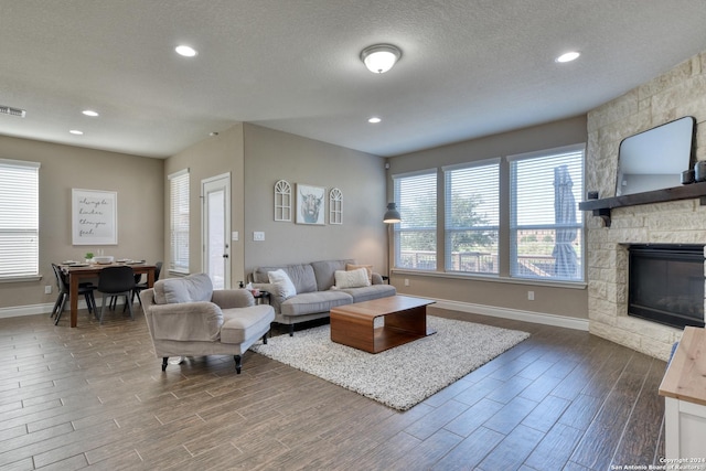 living room with a stone fireplace and a textured ceiling