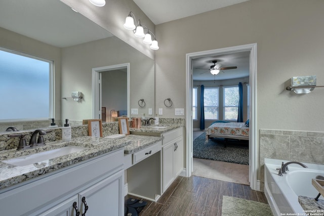 bathroom featuring vanity, a relaxing tiled tub, and ceiling fan