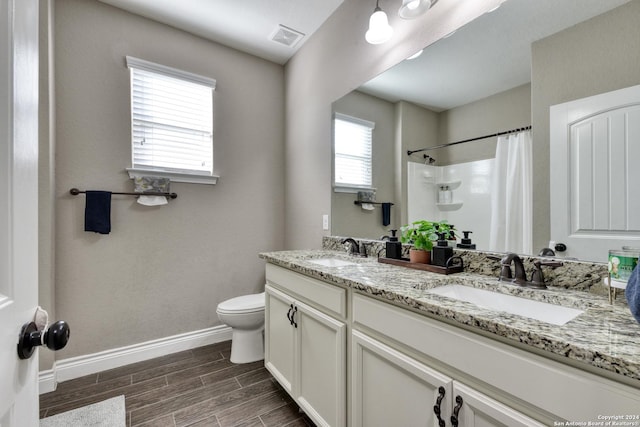 bathroom featuring vanity, toilet, curtained shower, and a healthy amount of sunlight