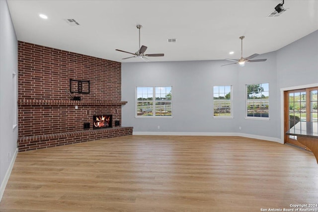 unfurnished living room featuring light wood-type flooring, brick wall, and a brick fireplace