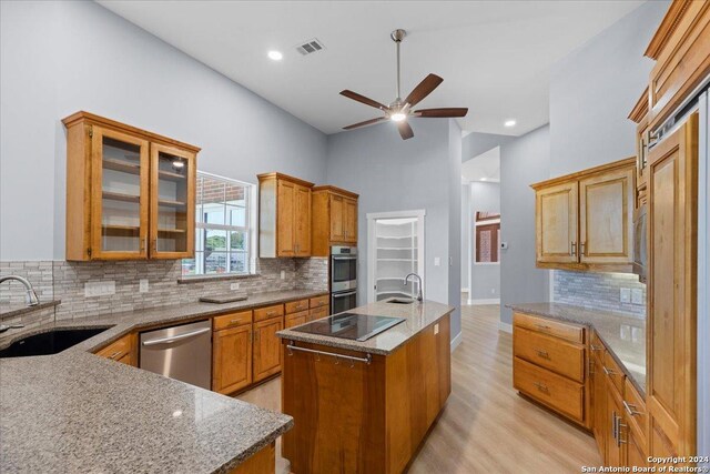 kitchen with sink, an island with sink, a high ceiling, and appliances with stainless steel finishes