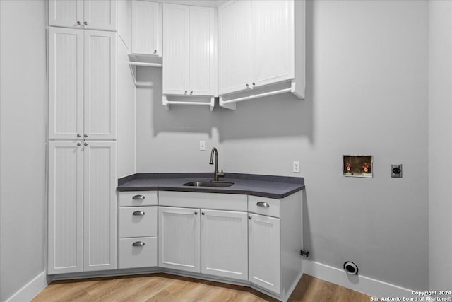 laundry area featuring electric dryer hookup, cabinets, sink, washer hookup, and light hardwood / wood-style floors