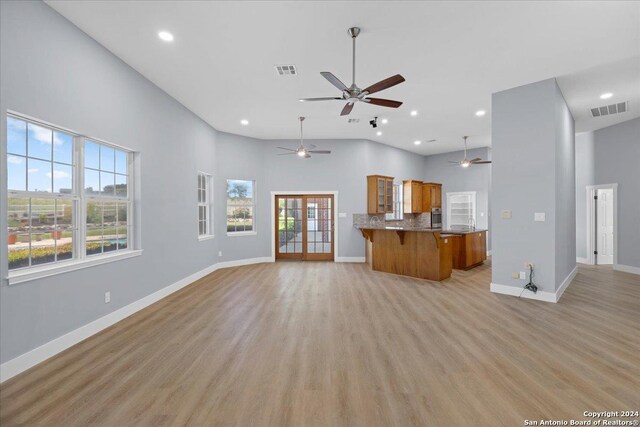 kitchen with kitchen peninsula, backsplash, a breakfast bar, light hardwood / wood-style flooring, and a high ceiling