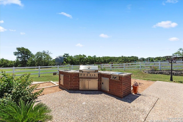 view of patio with an outdoor kitchen, a rural view, and grilling area