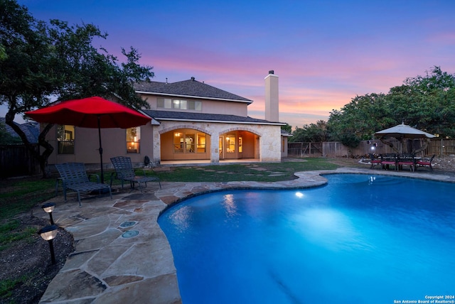 pool at dusk featuring a patio area