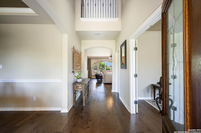 entryway with dark wood-type flooring, ceiling fan, and a towering ceiling