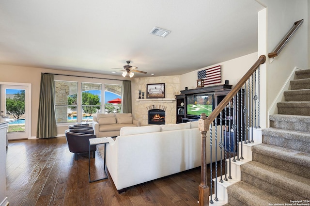 living room featuring a fireplace, dark wood-type flooring, and ceiling fan