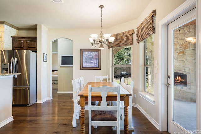 dining room featuring a chandelier, a fireplace, and dark hardwood / wood-style flooring