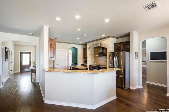 kitchen featuring light stone counters, dark hardwood / wood-style flooring, stainless steel fridge, and wall chimney exhaust hood