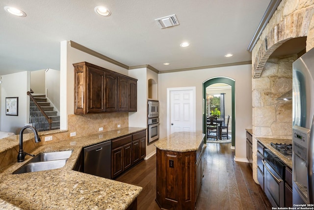 kitchen with sink, a center island, appliances with stainless steel finishes, light stone countertops, and backsplash