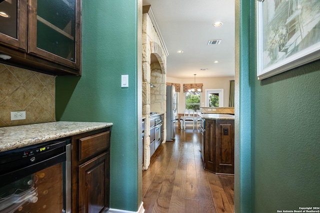 kitchen featuring hanging light fixtures, stainless steel refrigerator, dark hardwood / wood-style flooring, beverage cooler, and backsplash