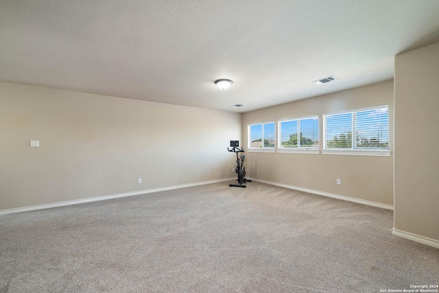 carpeted empty room featuring a textured ceiling