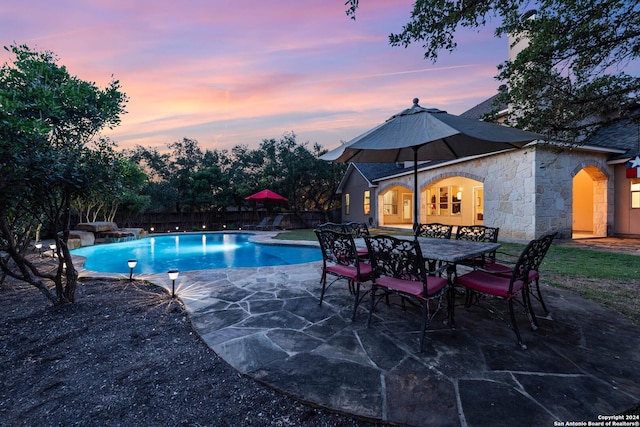 pool at dusk with a patio area