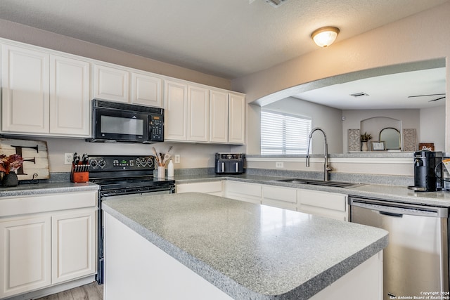 kitchen with sink, white cabinetry, black appliances, and a center island