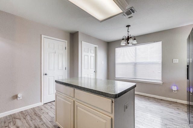 kitchen featuring hanging light fixtures, a kitchen island, light wood-type flooring, cream cabinets, and a notable chandelier