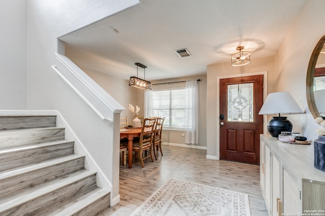 foyer with light hardwood / wood-style floors and a chandelier