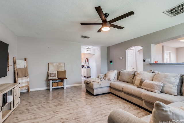 living room featuring light hardwood / wood-style flooring, a textured ceiling, and ceiling fan