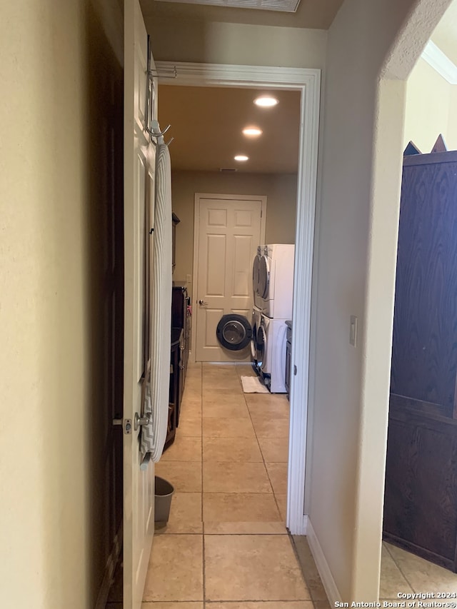 hall with stacked washer and clothes dryer and light tile patterned floors