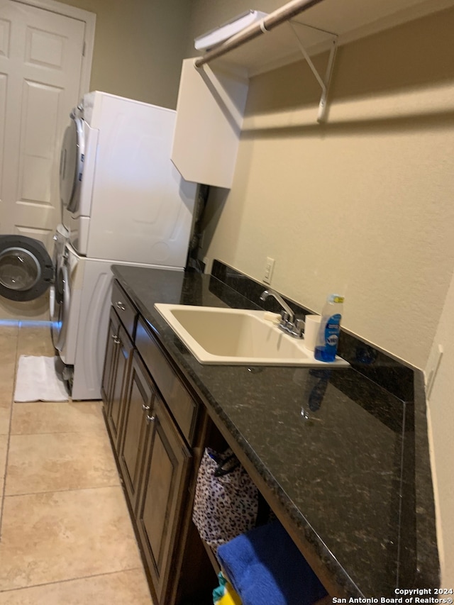 clothes washing area with stacked washer / dryer, sink, and light tile patterned floors