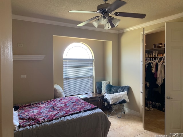 bedroom with light tile patterned flooring, a textured ceiling, ceiling fan, a closet, and ornamental molding