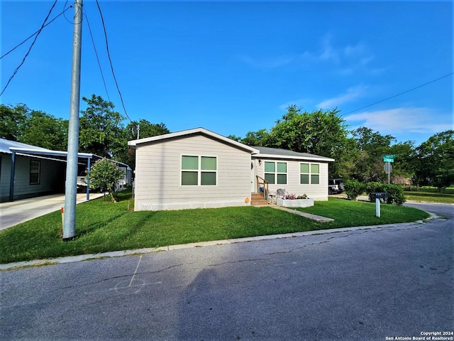 manufactured / mobile home with driveway, a carport, a front yard, and entry steps