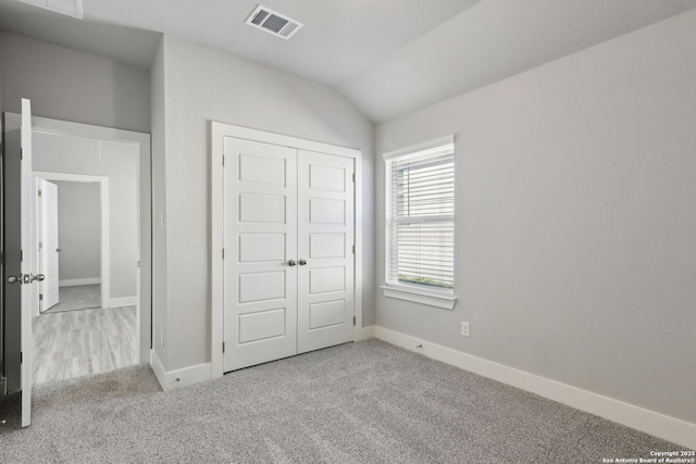 unfurnished bedroom with vaulted ceiling, a closet, and light carpet