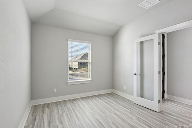 unfurnished bedroom featuring french doors, vaulted ceiling, and light hardwood / wood-style floors