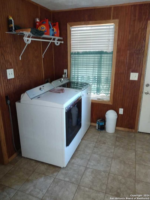 washroom featuring washer and clothes dryer, light tile patterned floors, and wooden walls