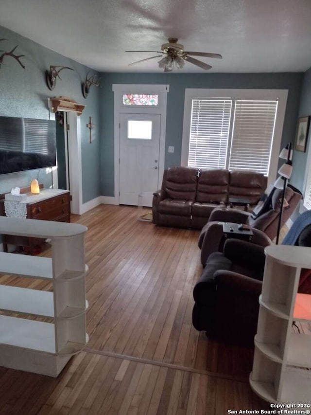 living room featuring a textured ceiling, light hardwood / wood-style flooring, and ceiling fan