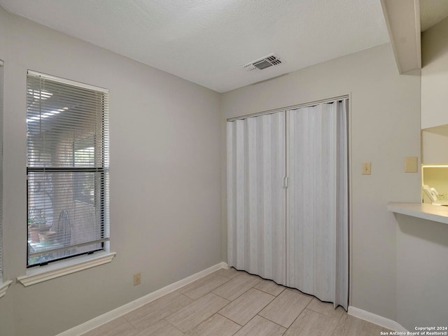 unfurnished bedroom featuring a textured ceiling, a closet, and light tile patterned floors