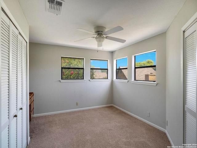 unfurnished bedroom featuring multiple windows, carpet floors, and ceiling fan