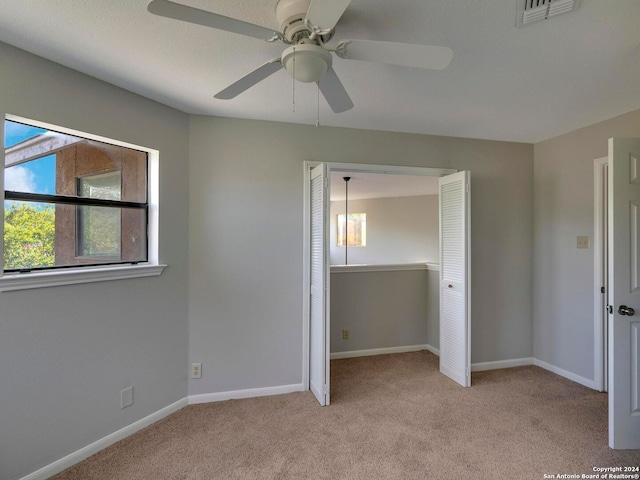 unfurnished bedroom featuring light colored carpet, a closet, and ceiling fan