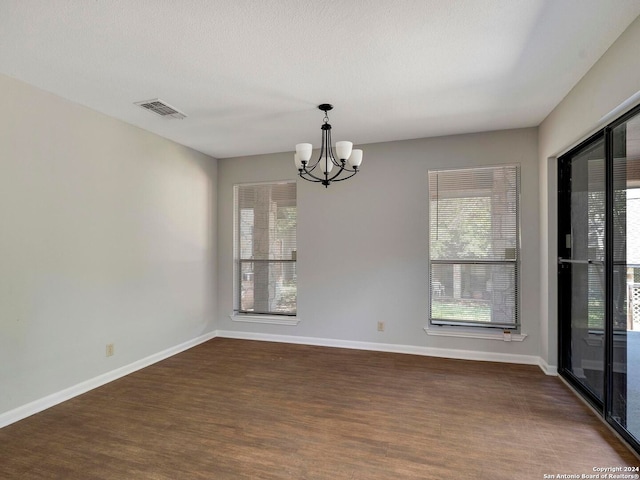 unfurnished room featuring dark hardwood / wood-style flooring and a notable chandelier