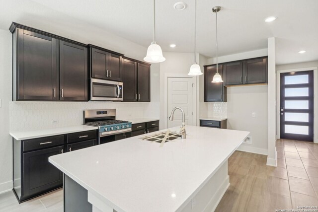 kitchen featuring stainless steel appliances, a center island with sink, sink, and decorative light fixtures