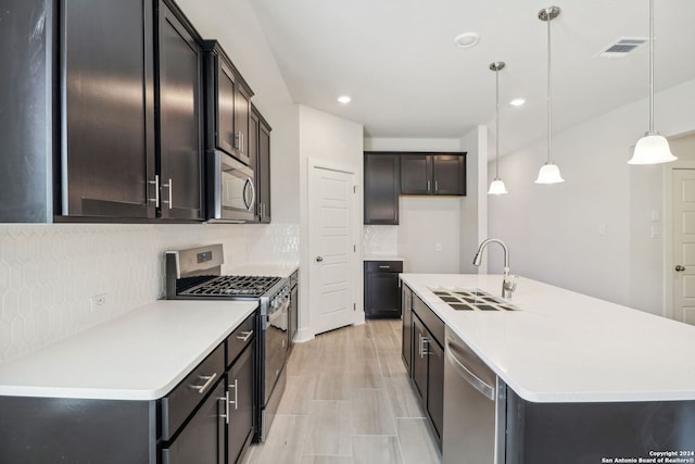 kitchen featuring sink, tasteful backsplash, an island with sink, pendant lighting, and appliances with stainless steel finishes