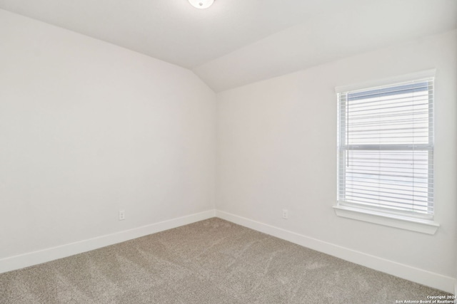 carpeted empty room with lofted ceiling